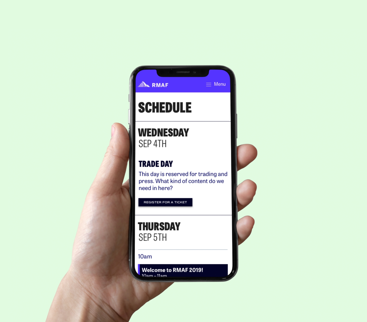 A hand holds a mobile phone which shows the top of the schedule for the festival
